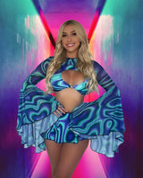 Beaming model in a blue wave-patterned rave ensemble against a vibrant pink and blue neon backdrop