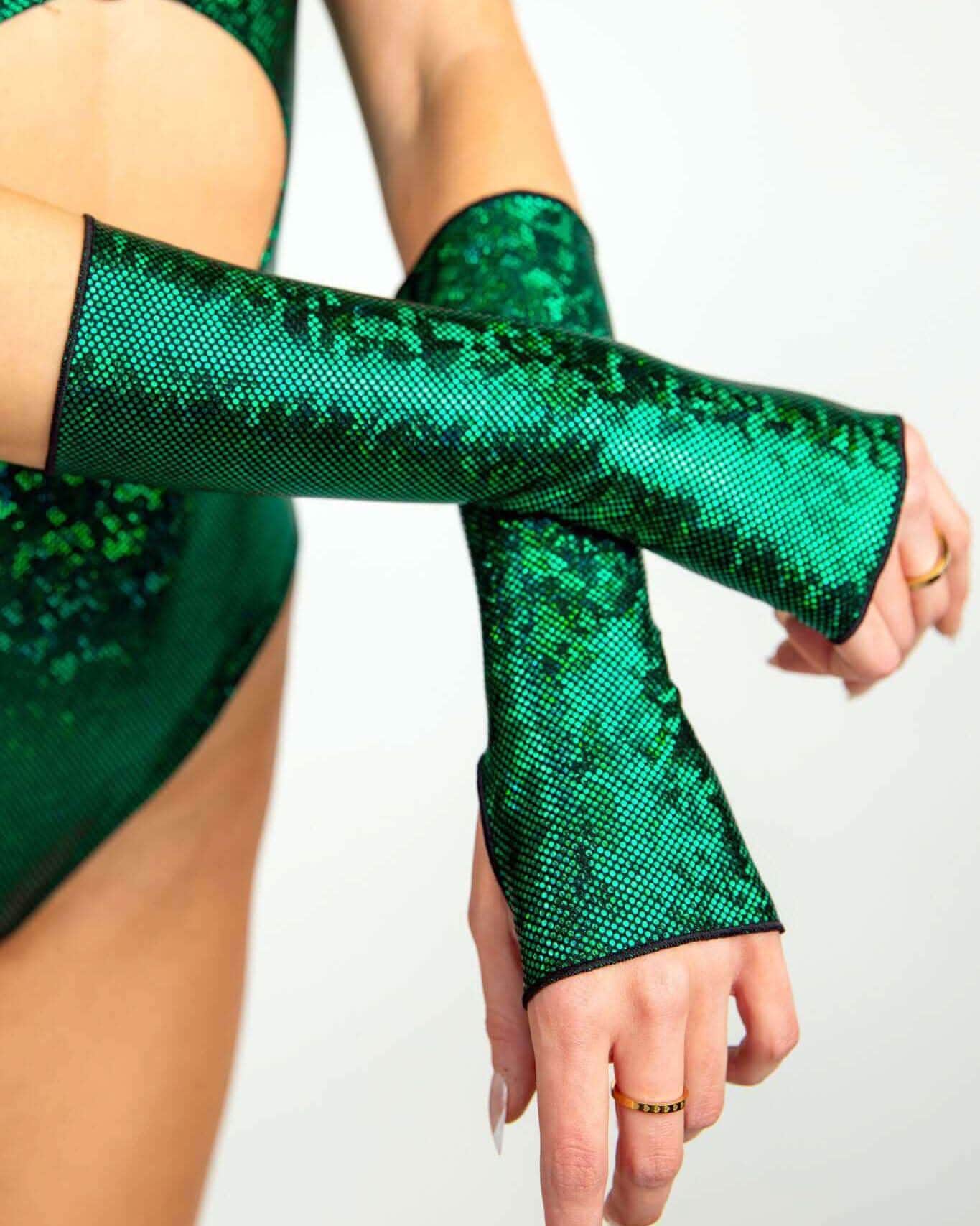 Model wearing emerald holographic rave arm sleeves in crossed arms pose for festival outfit styling