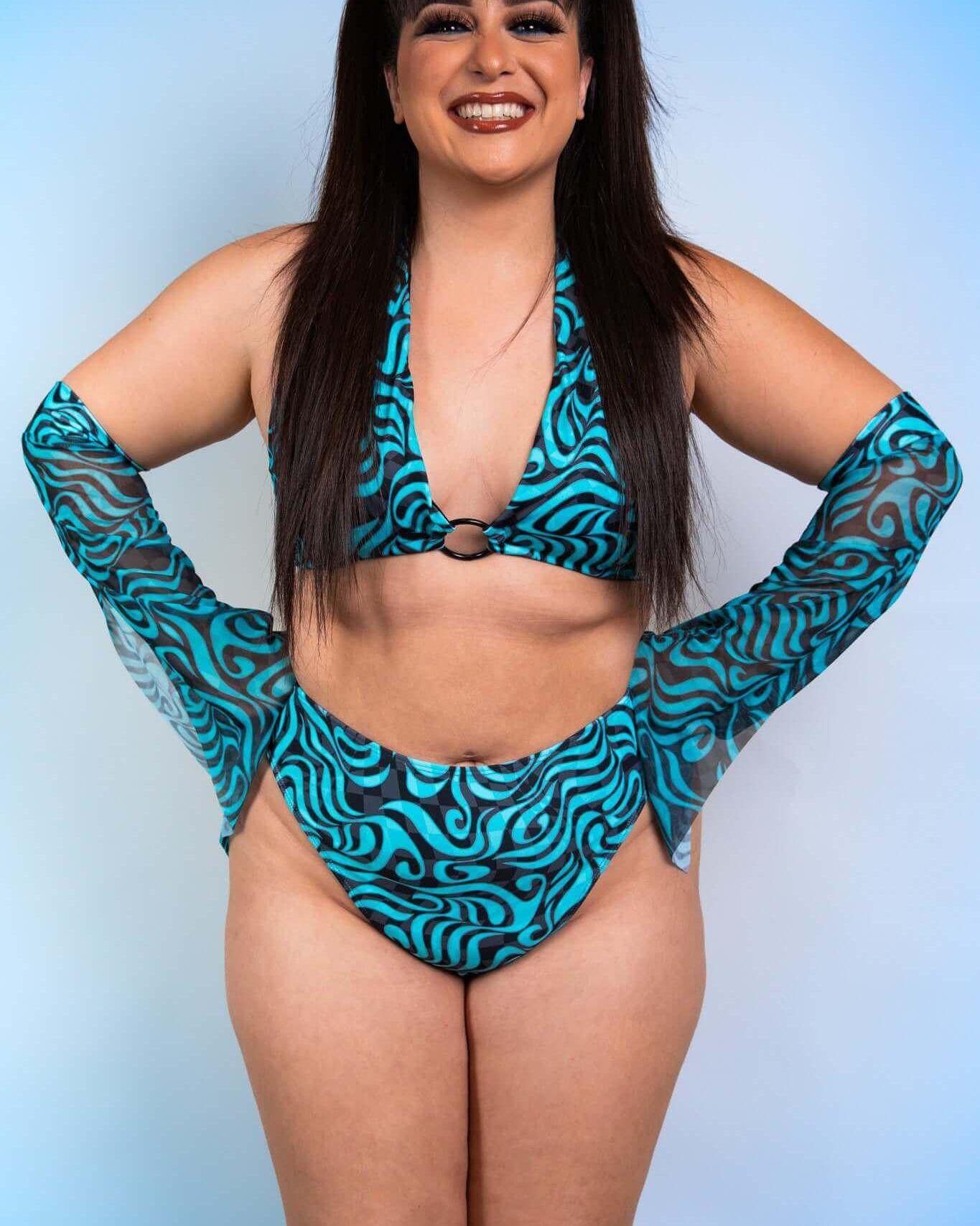 Woman in blue patterned rave outfit with Enigma Metamorphosis Sleeves, showcasing a stylish and vibrant festival look.