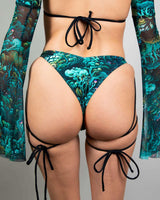 Faewood High Hip Strappy Bottoms showcasing unique strappy detail and vibrant forest print, ideal for rave outfits.