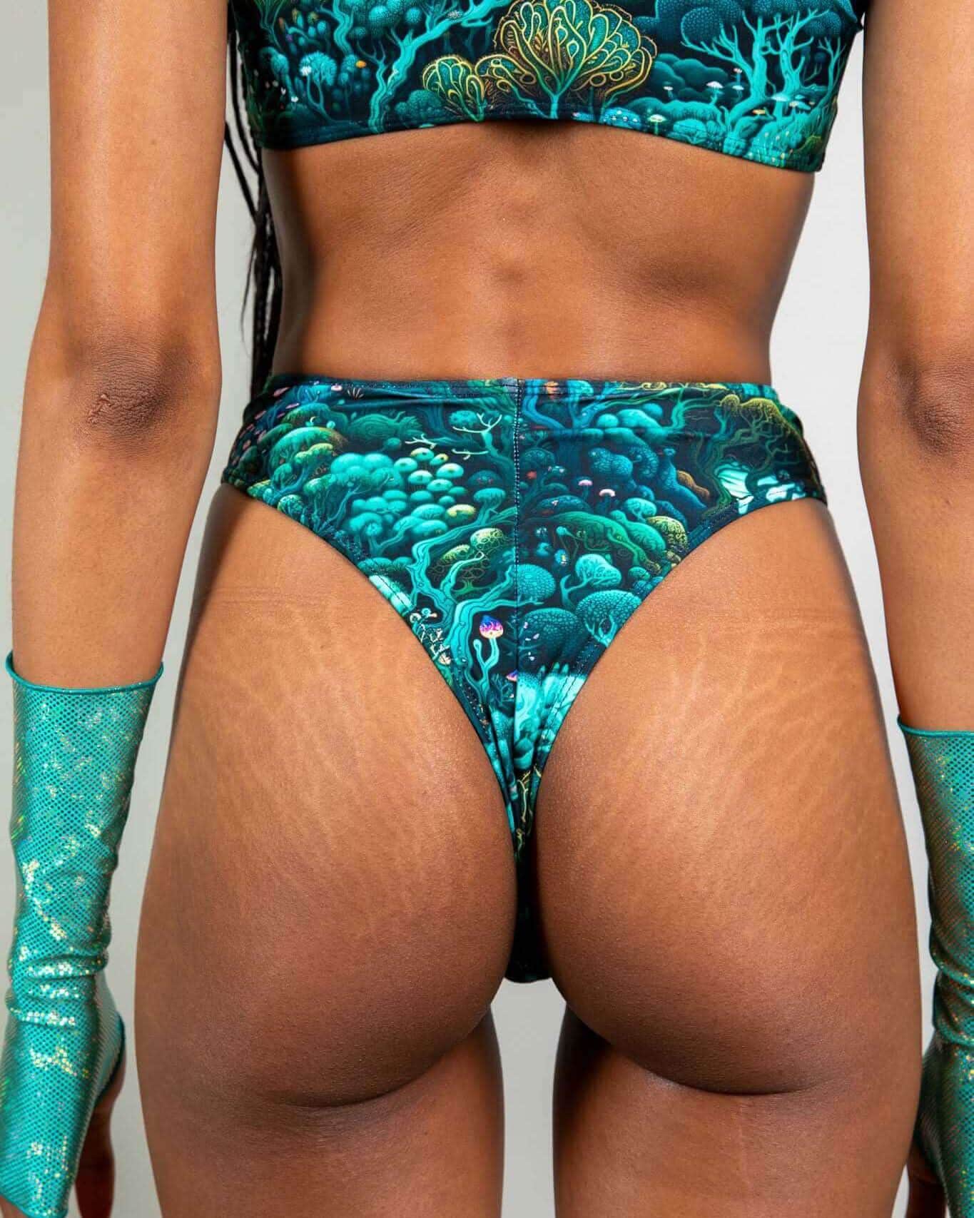 Model wearing Faewood High Waisted Thong, showcasing vibrant forest print and extra cheeky cut, perfect for rave outfits.