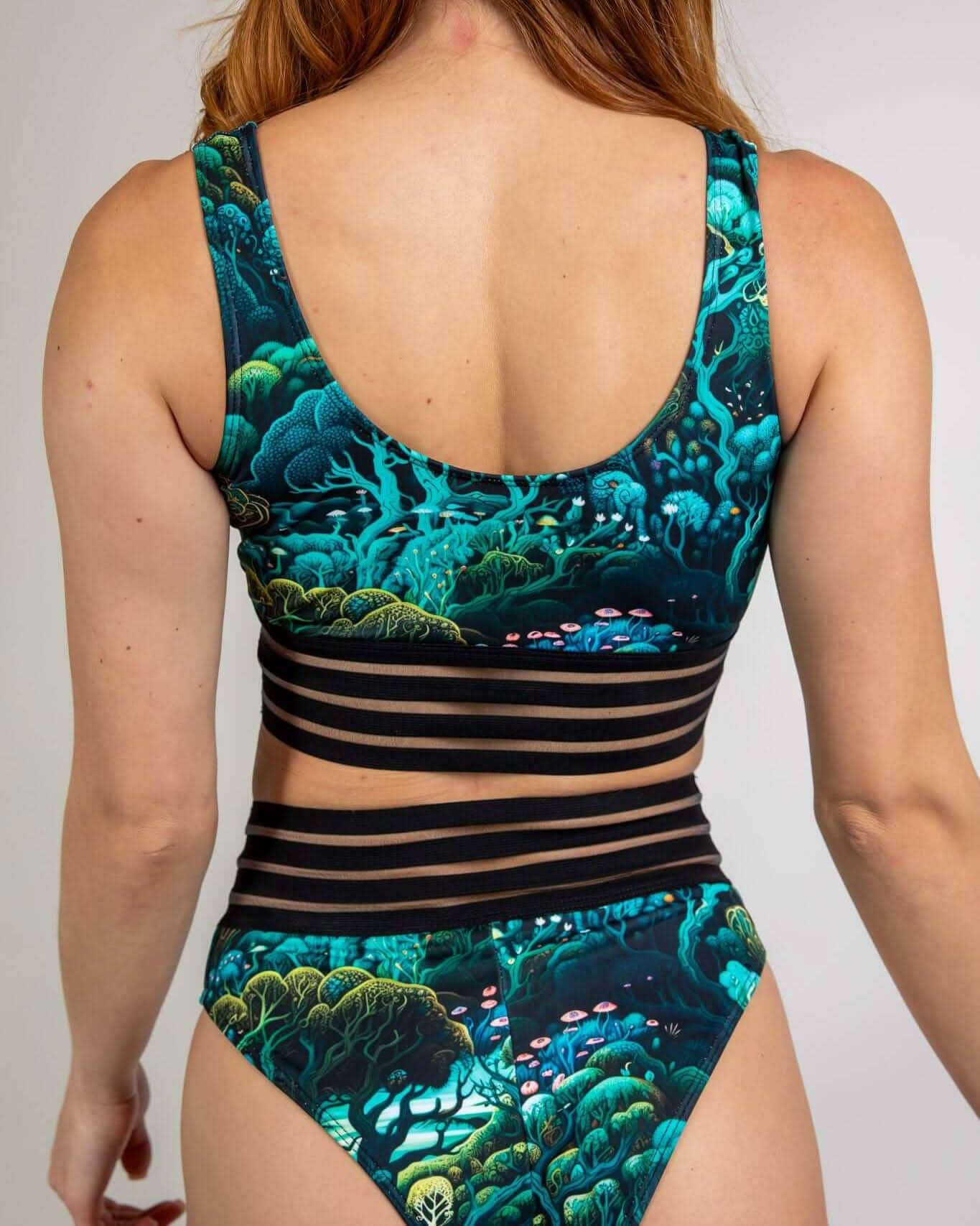 Back view of Faewood rave top with teal forest print and black elastic straps on model