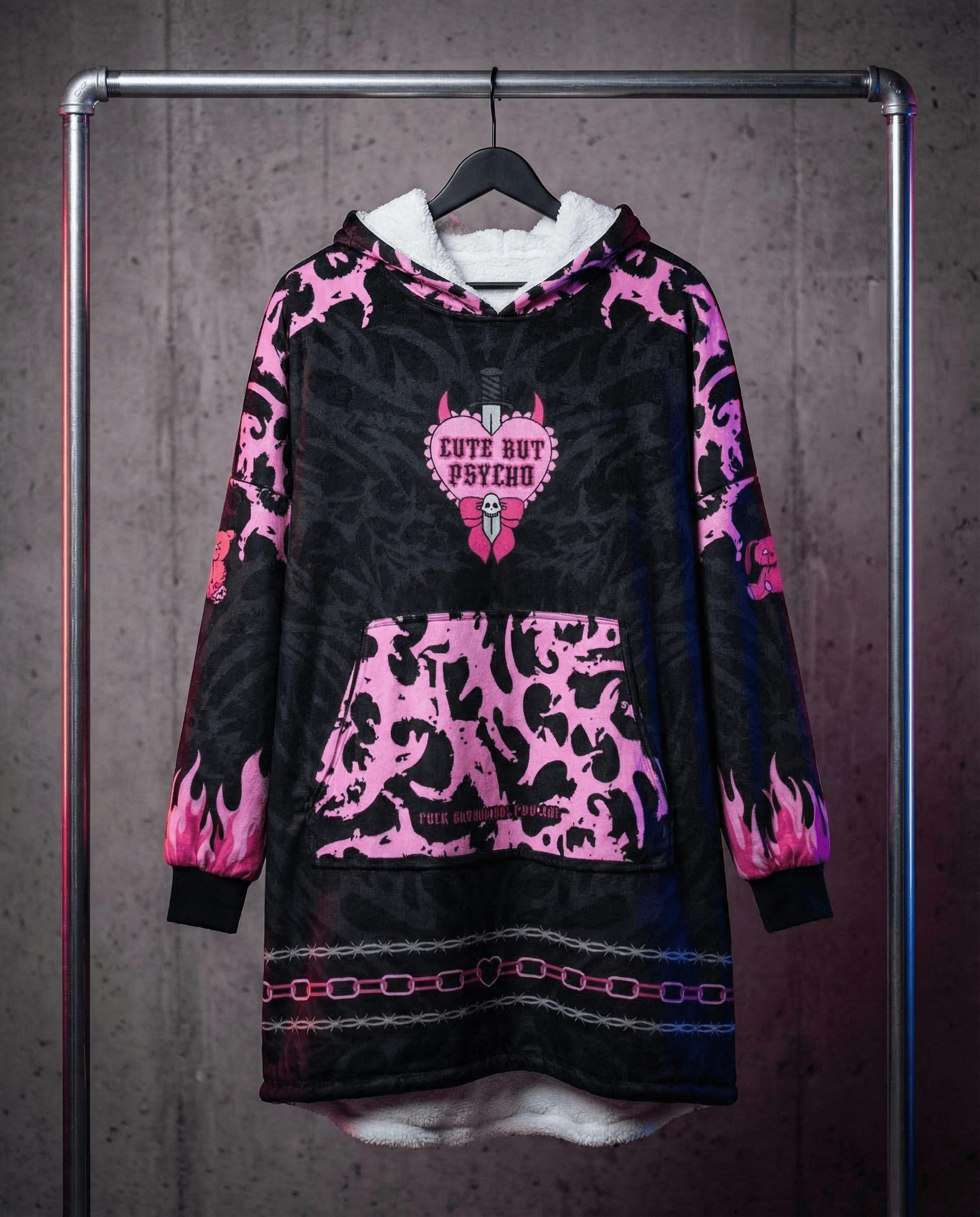 Festival hooded blanket in pink black pattern hanging on rack showing front view with hood and pocket