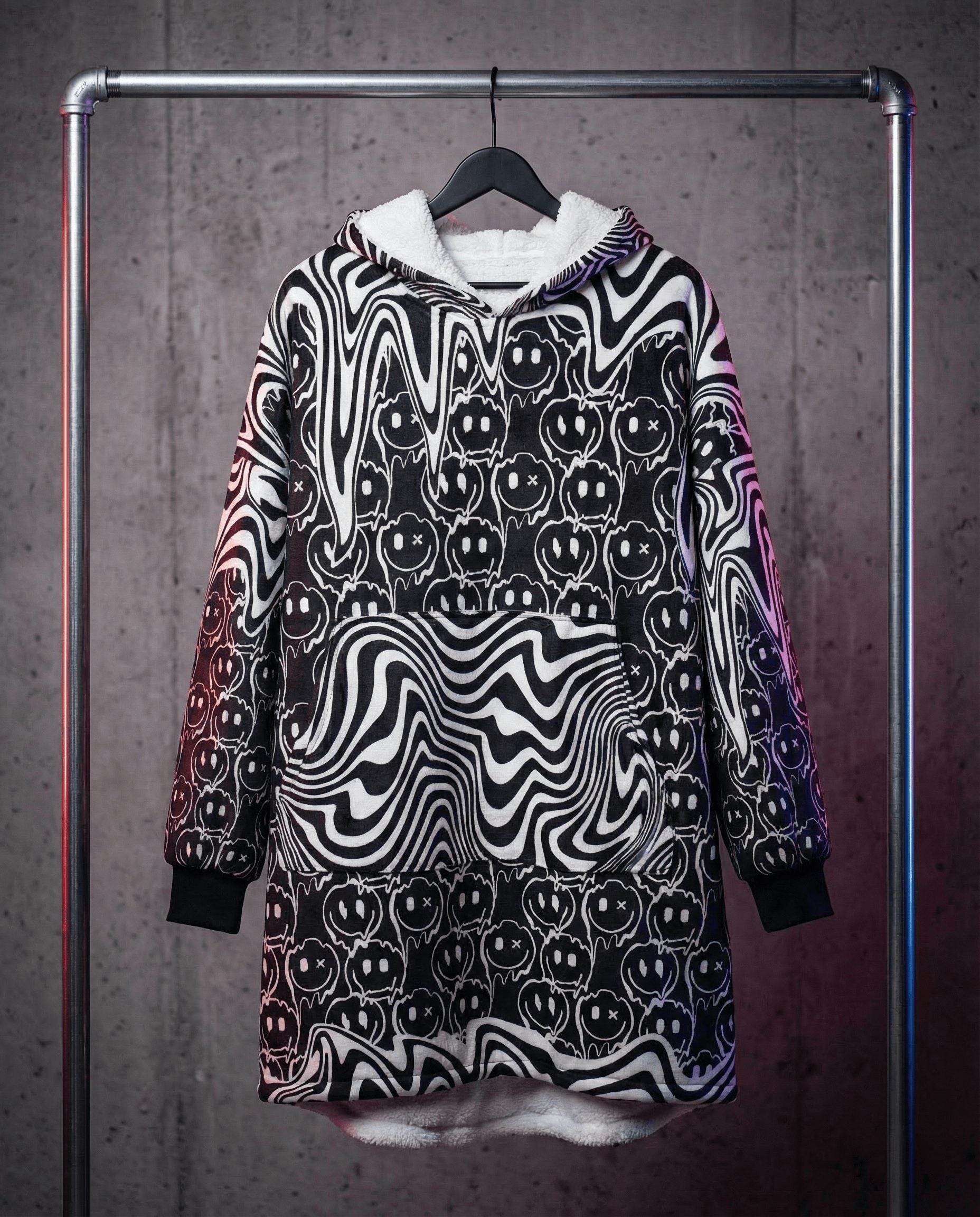 Festival hooded blanket with psychedelic smiley face print hanging on rack showing white fleece interior