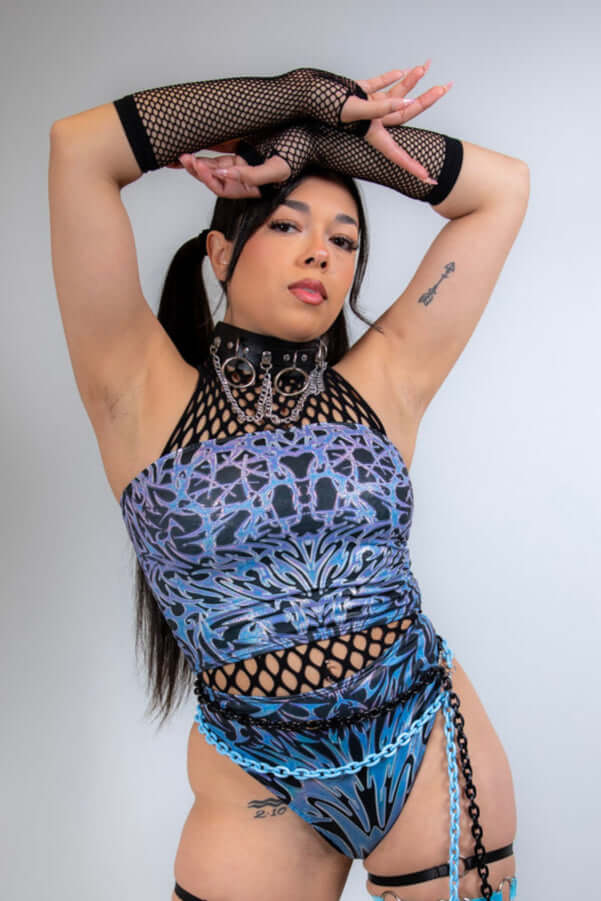 Model showcasing black fishnet arm sleeves as part of a vibrant rave outfit, posing confidently for the camera.