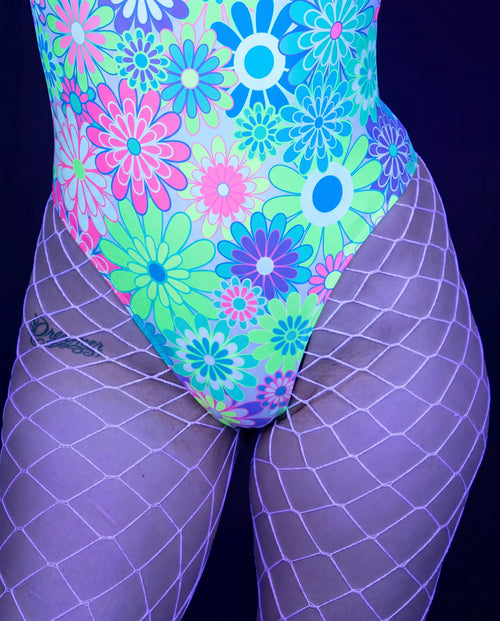 White fishnet stockings worn with colorful floral rave bodysuit for festival outfit styling — UV blacklight
