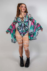 Model in a Flutter Goddess bodysuit with butterfly pattern, lace-up detailing, and flowy bell sleeves, showcasing rave outfits.