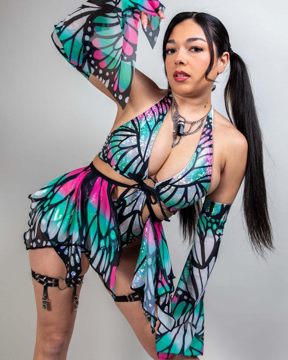 Woman modeling Flutter Metamorphosis Sleeves with butterfly pattern, showcasing stylish rave outfit and vibrant colors.
