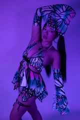 Model poses in a colorful butterfly print outfit, showcasing rave-inspired fashion with vibrant colors and fun accessories.