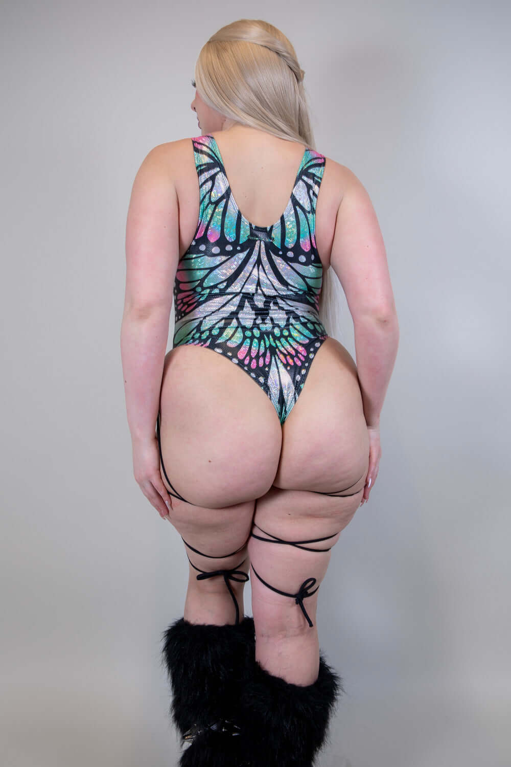 Back view of a woman in a Flutter Sideboob Bodysuit with leg straps and butterfly print, ideal for rave outfits.