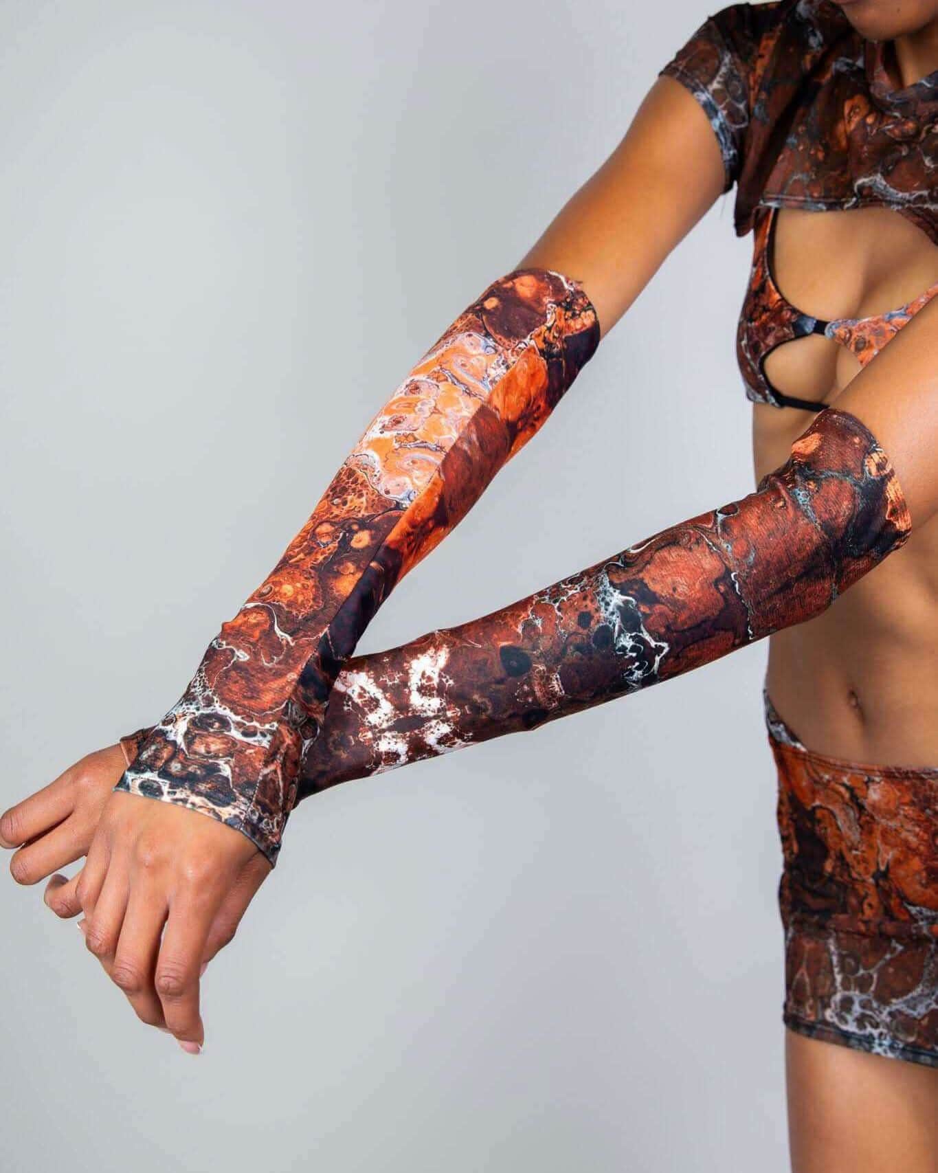 Model extending arms showing Fossil rave arm sleeves with brown marbled pattern in matching festival outfit