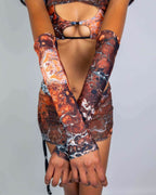 Model wearing Fossil rave arm sleeves in earthy brown marbled pattern, arms crossed showing full coverage