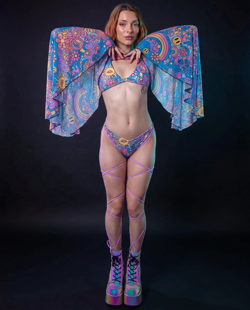 Groovy Mesh Bell Sleeves on a model from the front, showcasing the vibrant psychedelic pattern with suns, peace signs, and rainbows, perfect for a rave festival.
