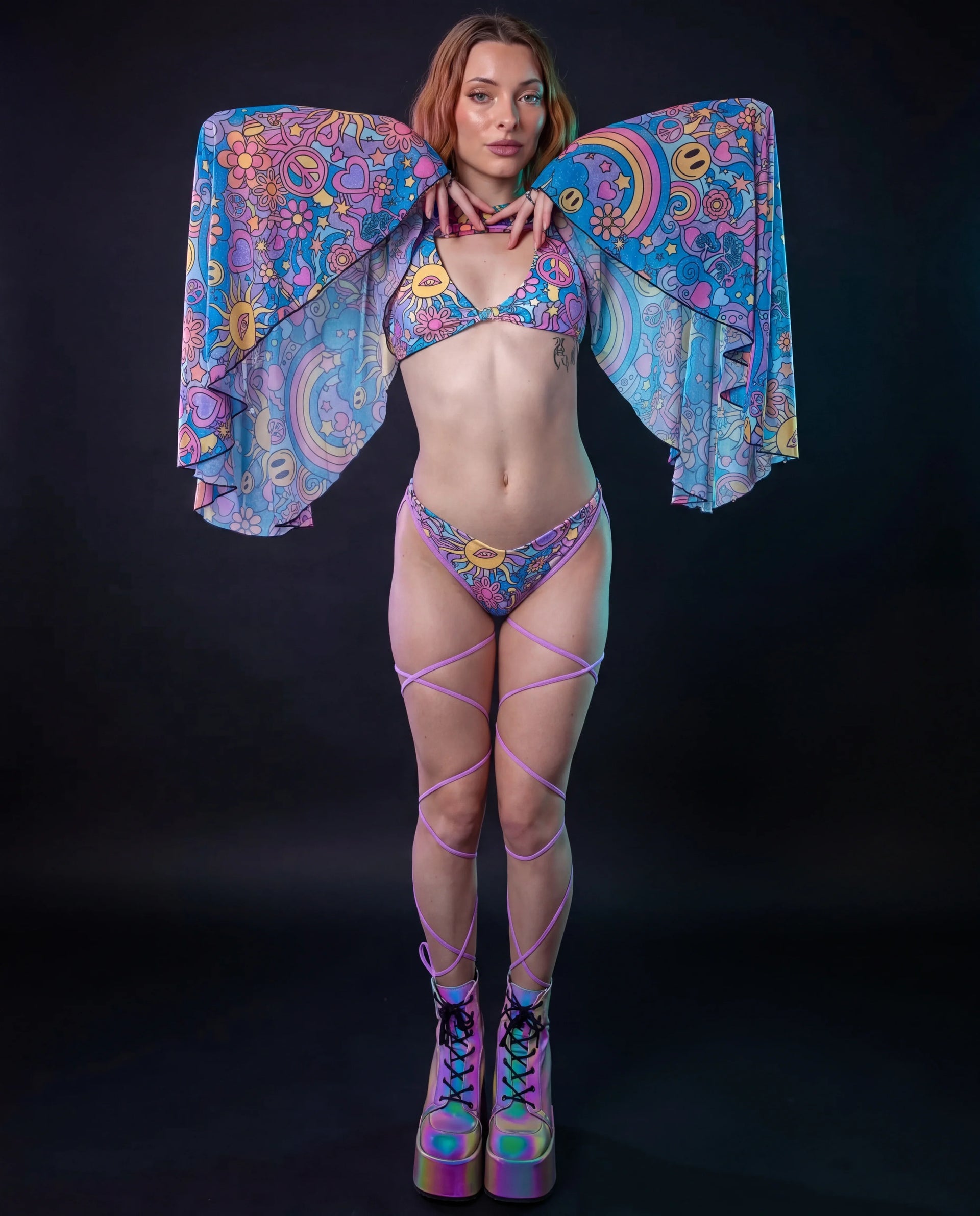 Groovy Mesh Bell Sleeves on a model from the front, showcasing the vibrant psychedelic pattern with suns, peace signs, and rainbows, perfect for a rave festival.