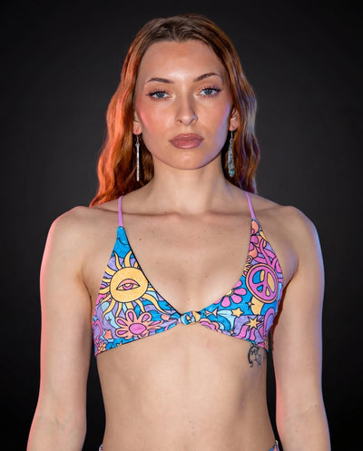 Groovy Serendipity Top front view, showcasing the pastel rave bikini top with peace signs, daisies, and a third-eye sun.