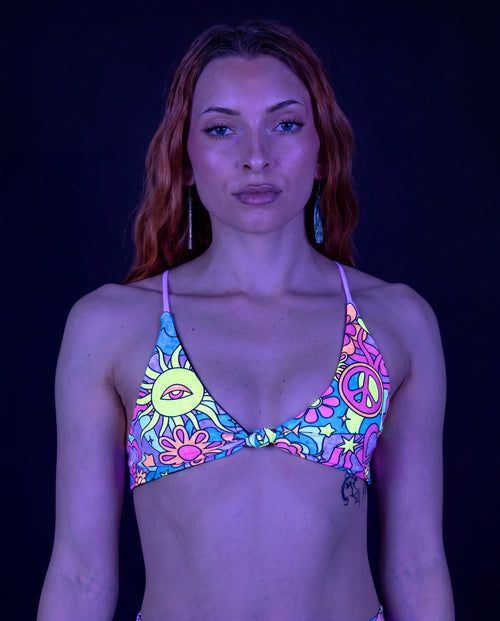 Groovy Serendipity Top front view, showcasing the pastel rave bikini top with peace signs, daisies, and a third-eye sun. — UV blacklight