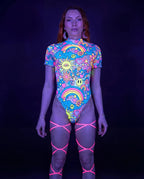Groovy Wavy Baby Bodysuit front view, featuring a vibrant psychedelic pattern with smiley faces, mushrooms, and rainbows, perfect for rave festivals. — UV blacklight