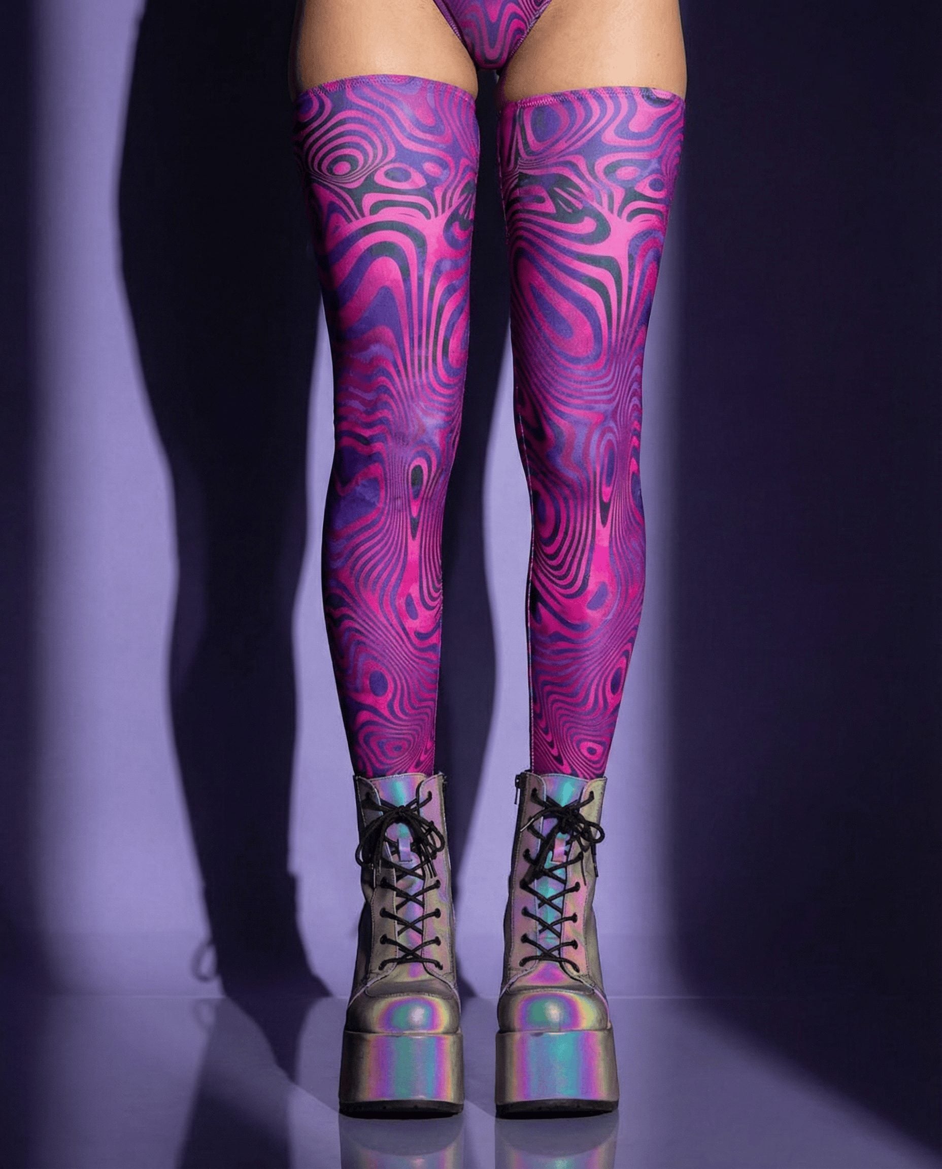 Alt Tag: Vanish Leg Sleeves electric purple and pink swirl thigh-high leg sleeves with rave boots, psychedelic festival look