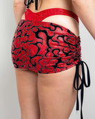 Woman wearing red and black ruched shorts with adjustable ties, perfect for rave outfits and stylish summer looks.