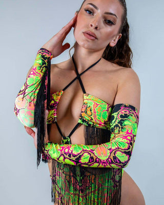 Model wearing vibrant Intensity Arm Sleeves with Fringe, showcasing bold UV patterns and playful black fringe.