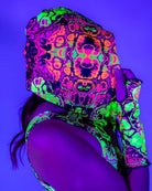 Woman wearing Intensity Assassin Hood with vibrant UV print, showcasing rave outfits style in a colorful setting.
