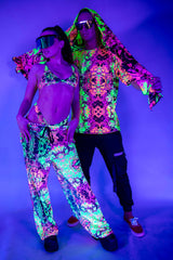Couple in vibrant neon rave outfits posing under UV light, showcasing colorful festival fashion and accessories.