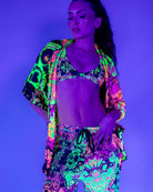 Model showcasing vibrant neon rave outfit featuring skull patterns, perfect for festivals and night events.