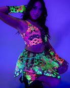 Model wearing UV reactive rave outfit featuring colorful gloves and skirt under blacklight.