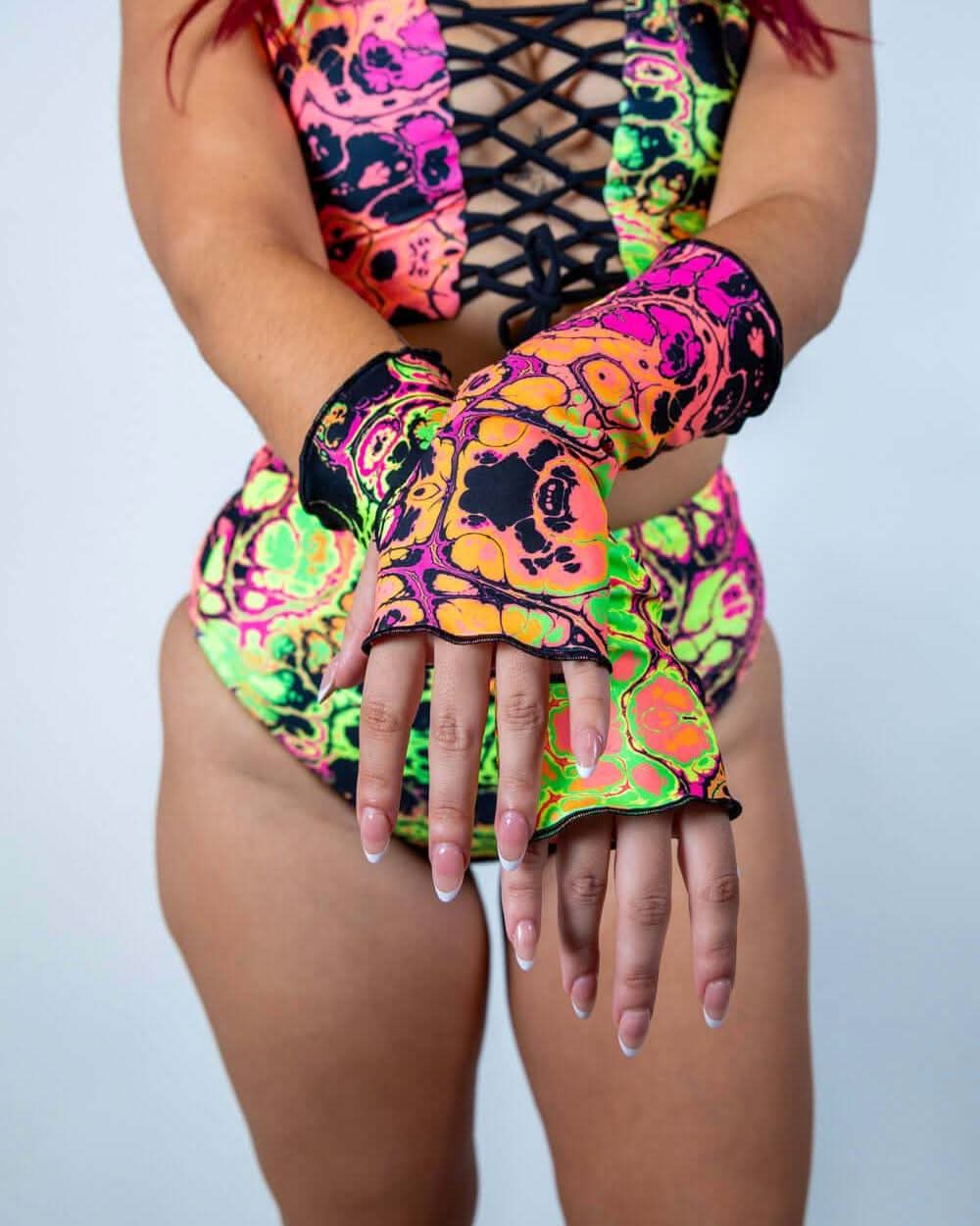 Model showcasing colorful Intensity Gloves, perfect for rave outfits with a vibrant skull design and thumb holes.