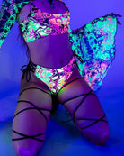 Model showcasing colorful Intensity Lace Up Brazilian Bottoms under UV light, perfect for rave outfits and swim.