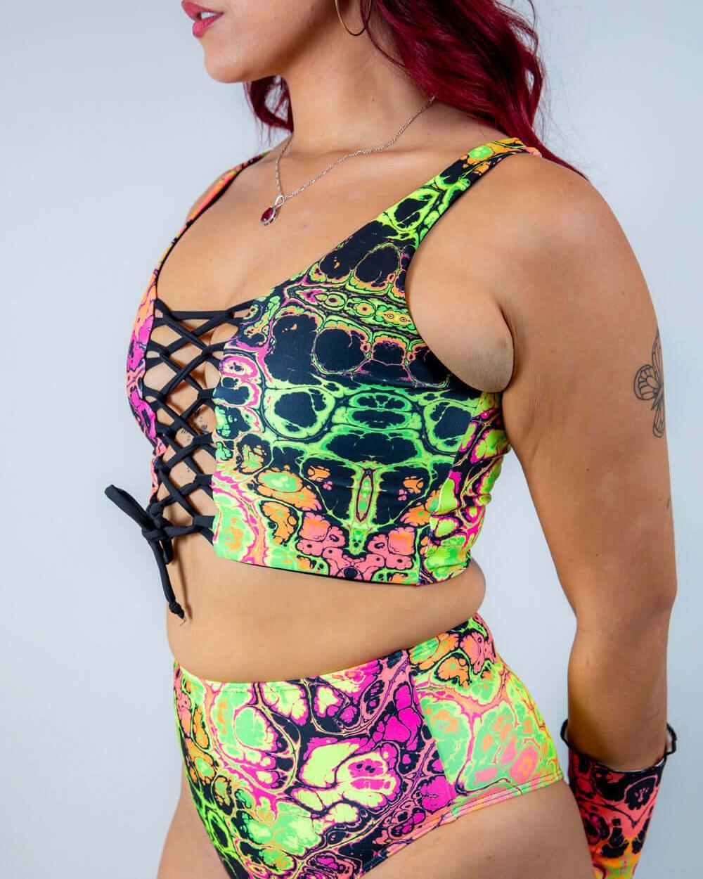Vibrant model wearing Intensity Lace Up Top with lace front, showcasing colorful UV reactive fabric, ideal for rave outfits.