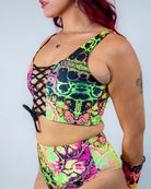 Vibrant model wearing Intensity Lace Up Top with lace front, showcasing colorful UV reactive fabric, ideal for rave outfits.
