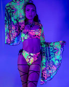 Model showcasing vibrant Intensity Mesh Bell Sleeves with UV reactive patterns, perfect for rave outfits.