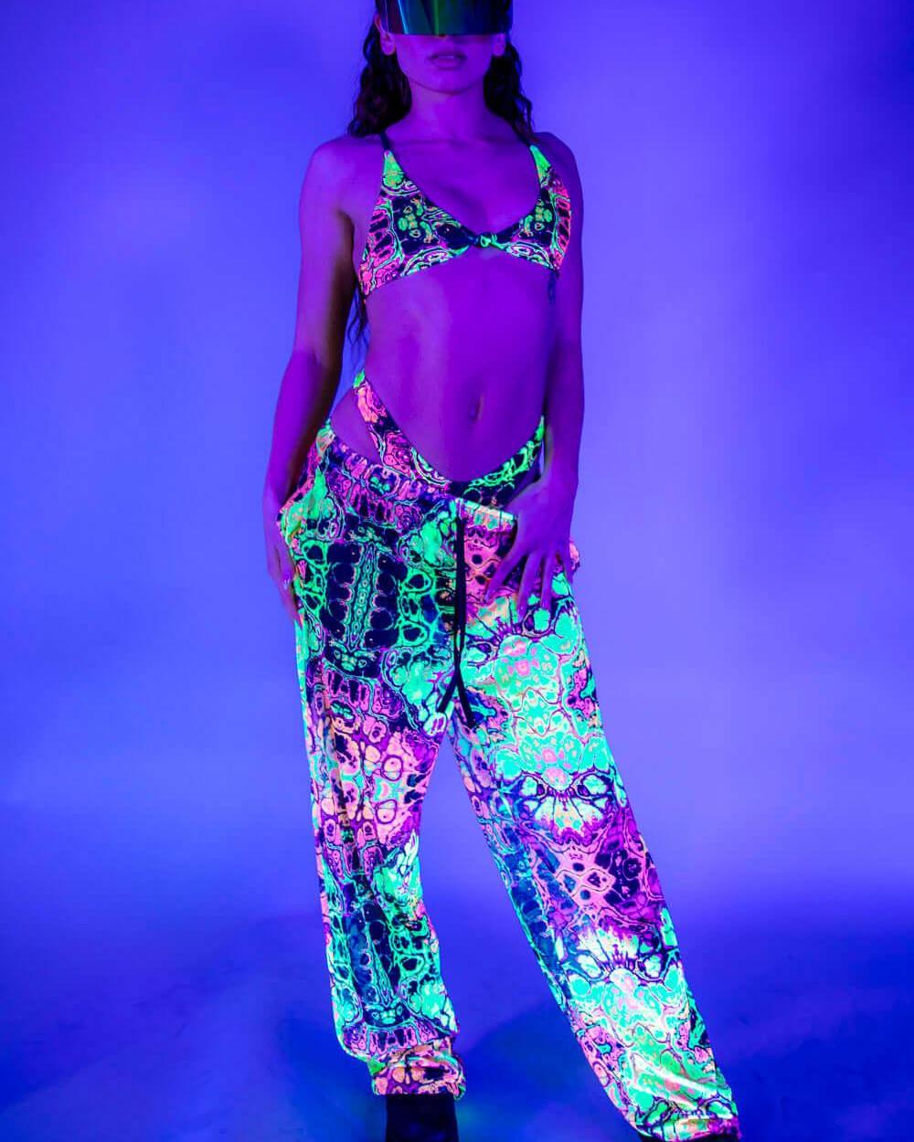 Front view of Intensity Mesh Lucy Pants under UV light, glowing in vibrant neon colors.