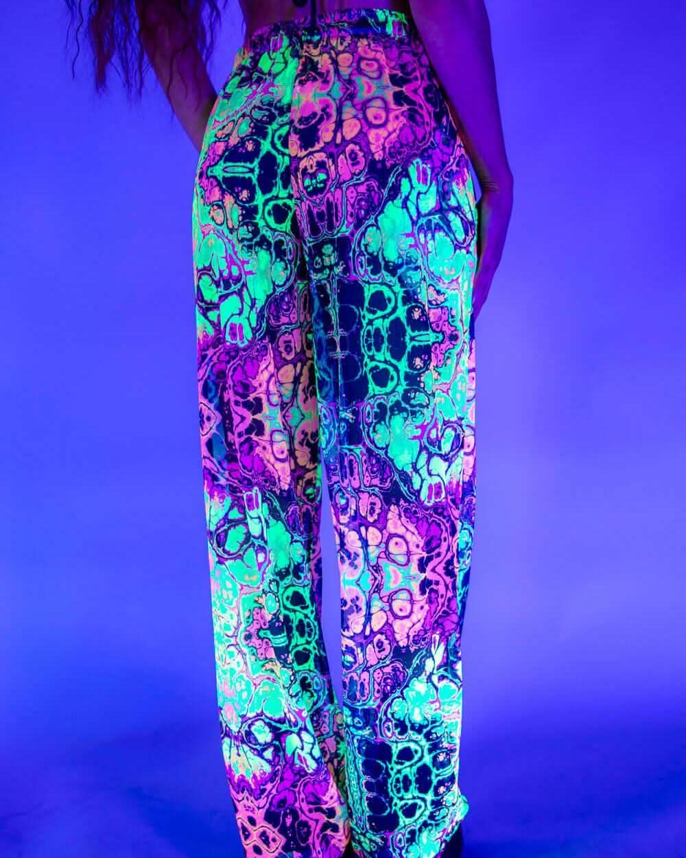 Rave bodysuit style Intensity Mesh Lucy pants glowing in neon colors under blacklight at festival