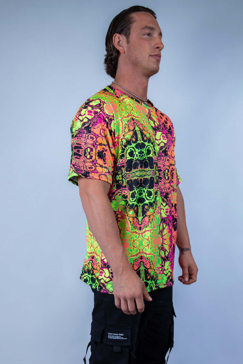 Man wearing a vibrant Intensity Oversized Softee t-shirt, featuring a colorful UV reactive print, ideal for rave outfits.