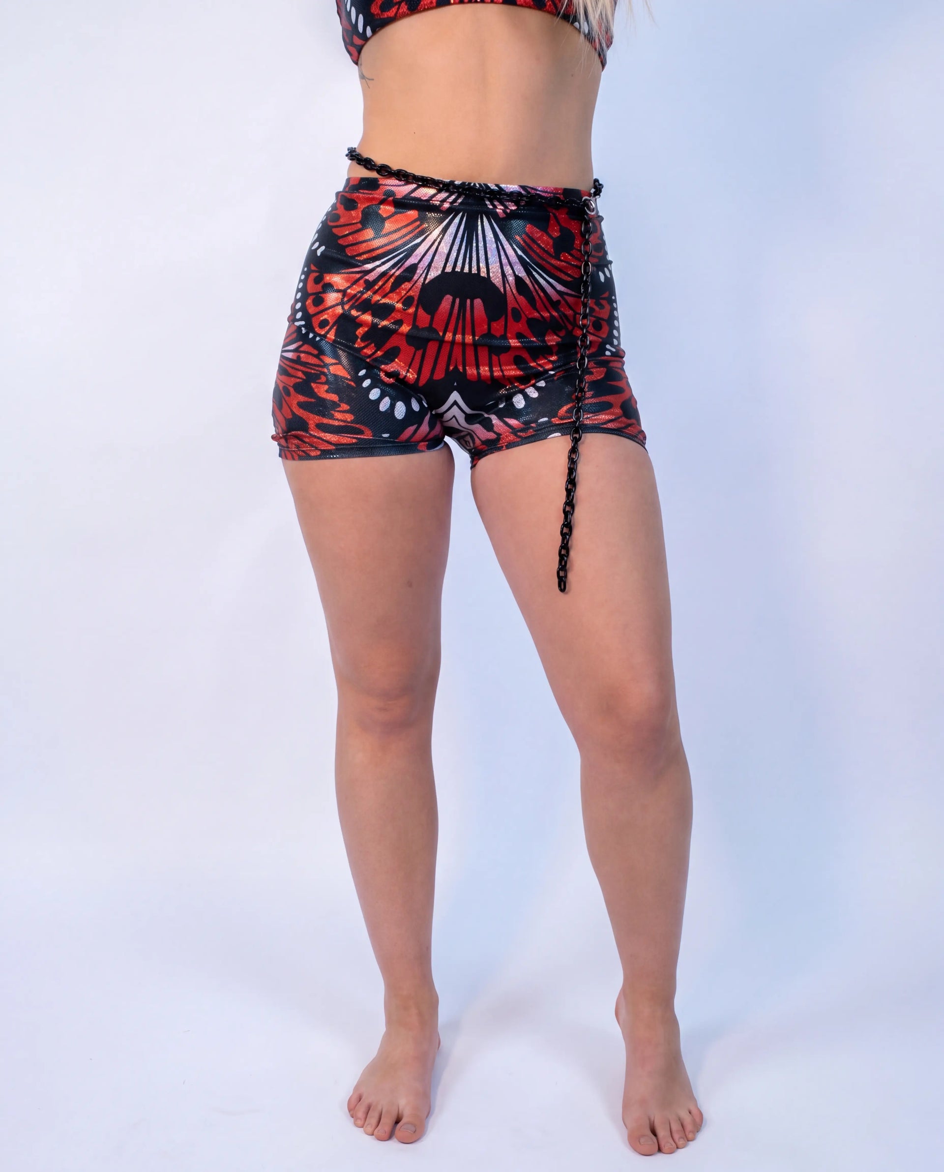 Lacewing High Waist Shorts in a vibrant red and black butterfly wing pattern, worn by a model from the front, perfect for rave or festival fashion. — white
