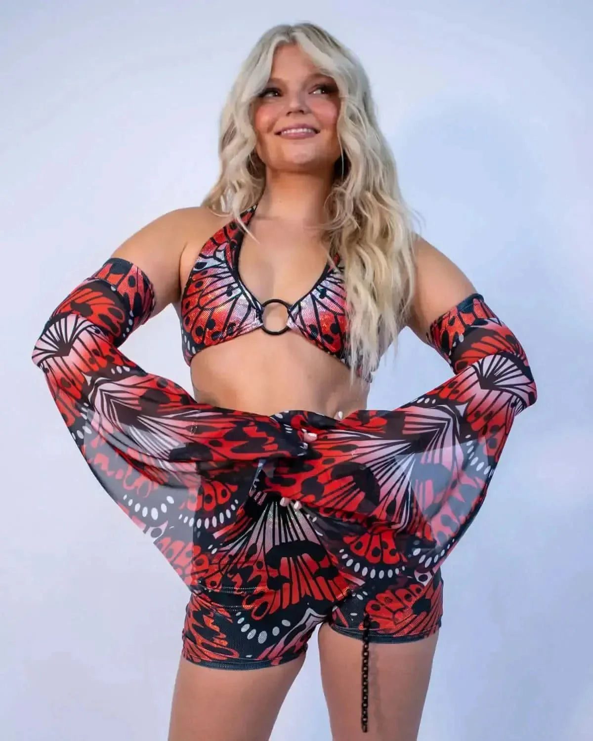 Model wearing red black Lacewing Metamorphosis rave arm sleeves with matching crop top festival outfit front view