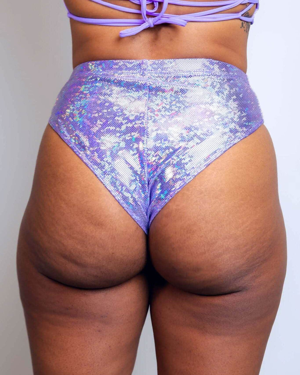 High-waisted lavender holographic Brazilian bottoms showcasing a cheeky cut, perfect for rave outfits.