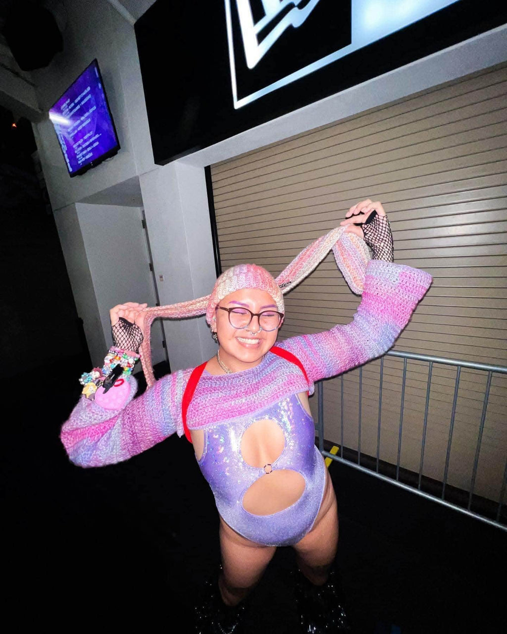 Trendy rave outfit featuring a Lavender Holo Keyhole Bodysuit with colorful accessories and playful hairstyle.