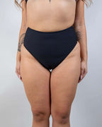 Matte black high waisted rave pants bikini bottoms front view festival outfit modeling shot
