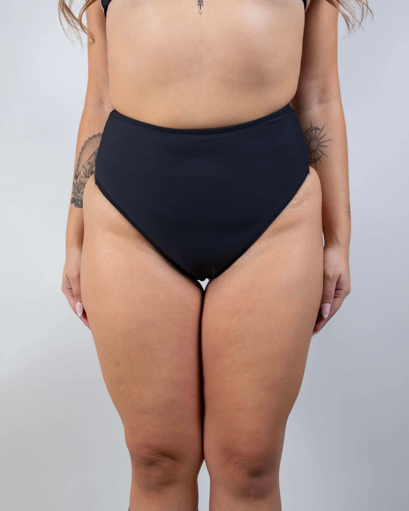 Matte black high waisted rave pants bikini bottoms front view festival outfit modeling shot