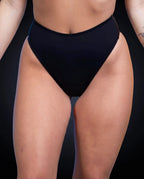 Matte black high waisted thong rave pants modeled from front view for festival outfit styling