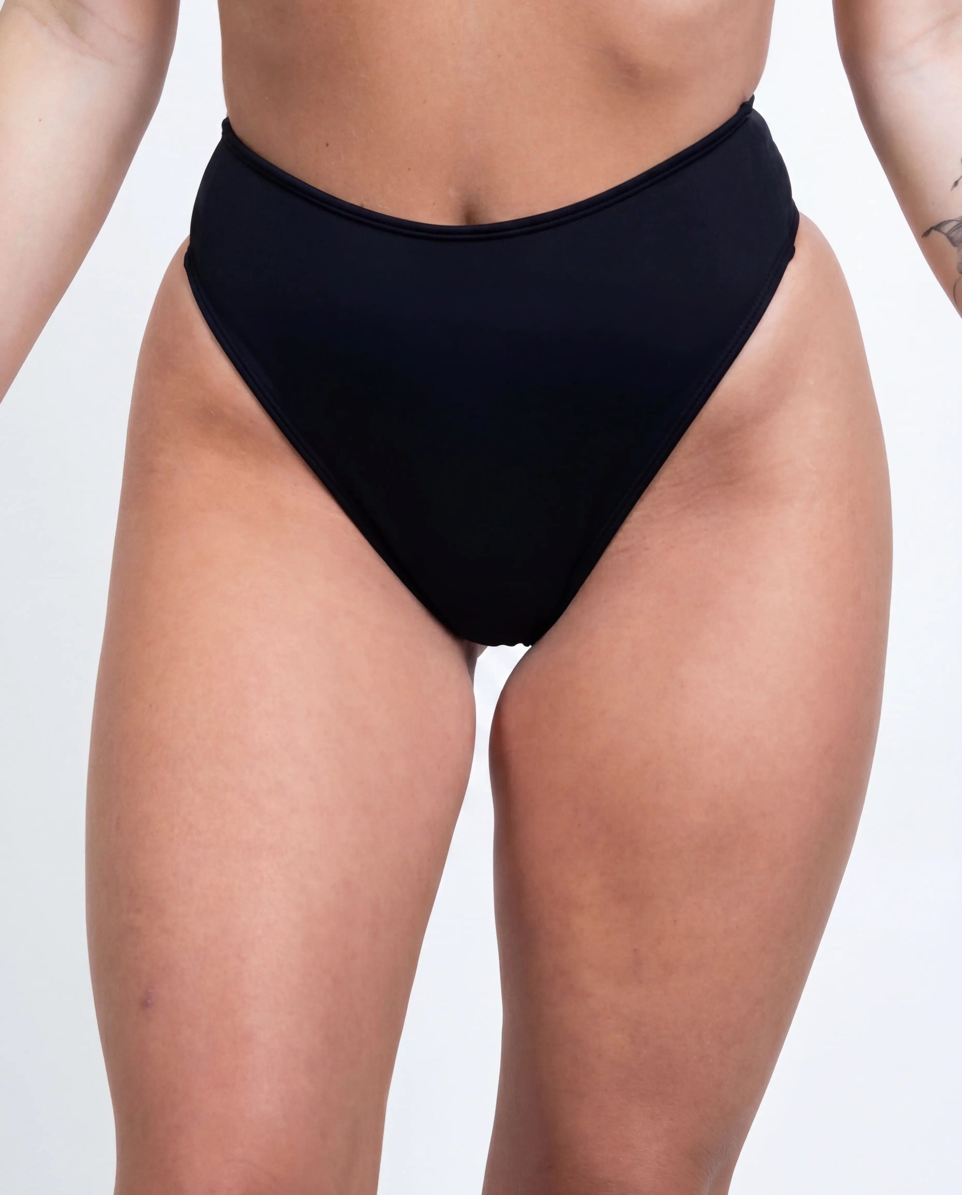 Matte black high waisted thong rave pants modeled from front view for festival outfit styling — white