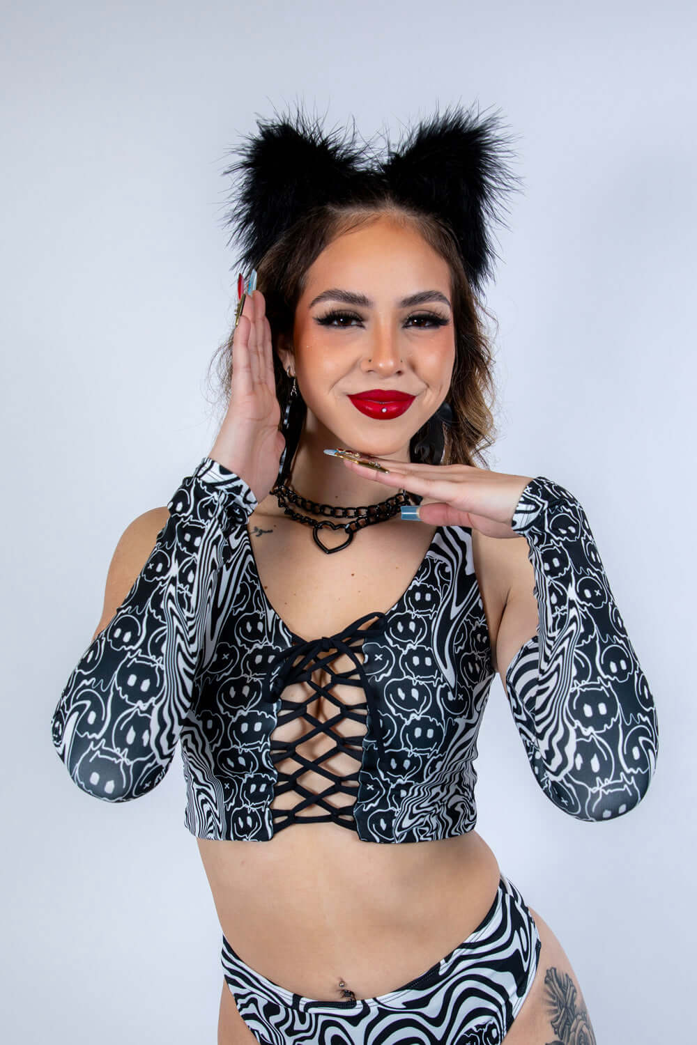 Model wearing Meltdown Arm Sleeves in front-facing pose with hands near face, showcasing the trippy melty smiley print.