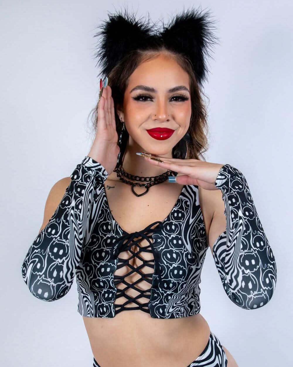 Model wearing Meltdown Arm Sleeves in front-facing pose with hands near face, showcasing the trippy melty smiley print.