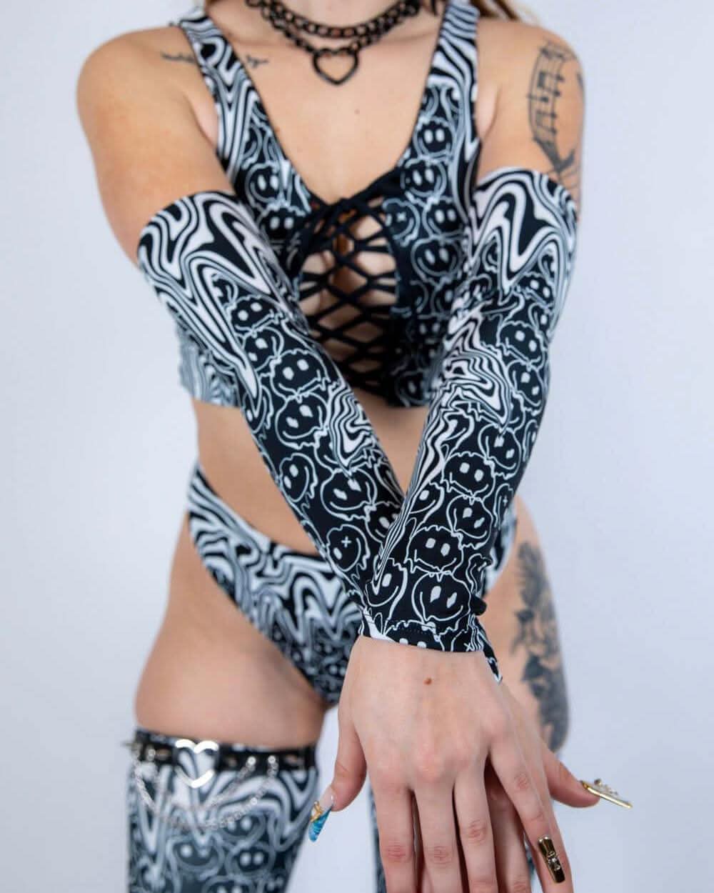 Model crossing arms while wearing Meltdown Arm Sleeves, highlighting their full length and vibrant trippy design.
