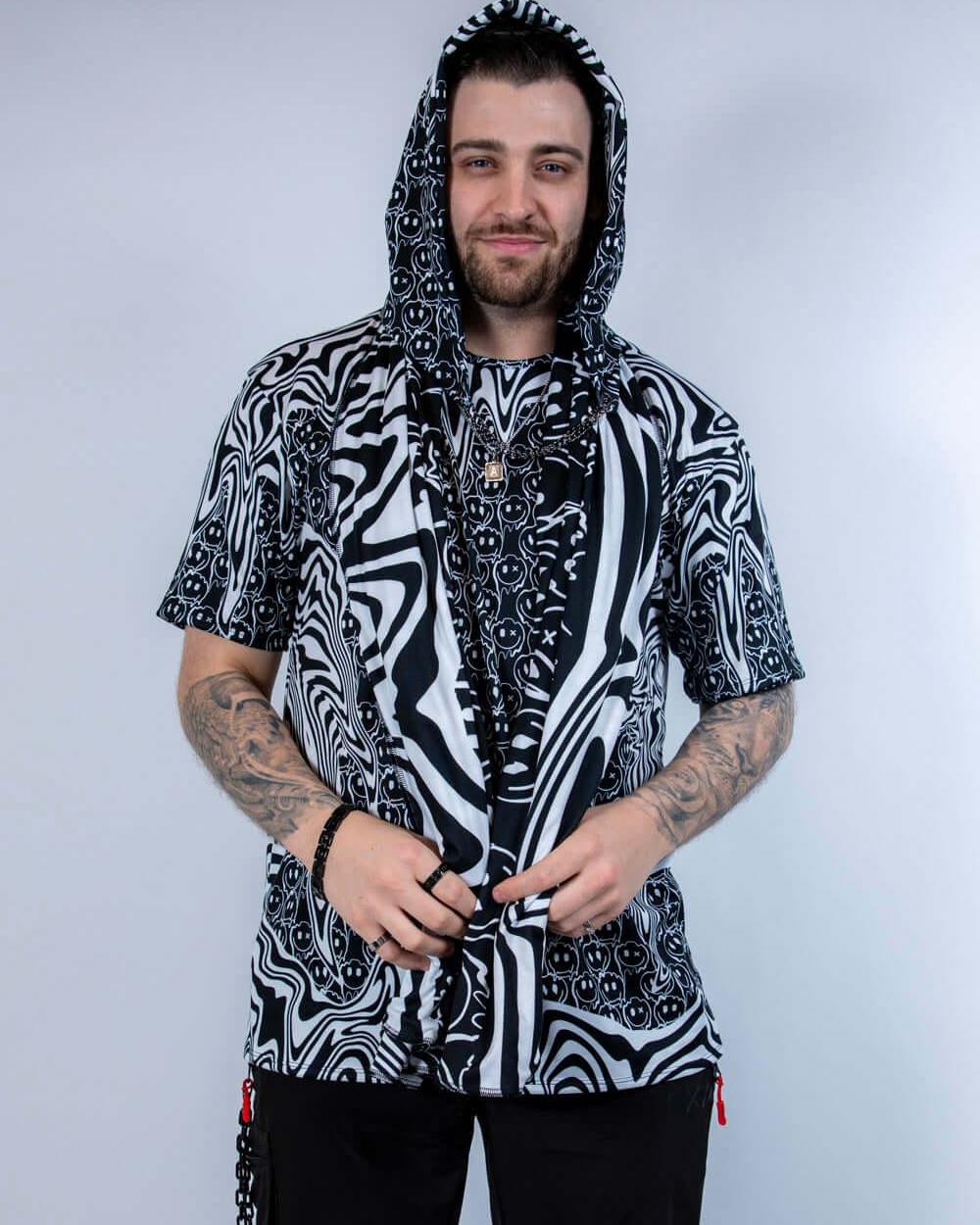 Model wearing the Meltdown Assassin Hood in full front view, holding the edges of the hood to show off the melty smiley print.
