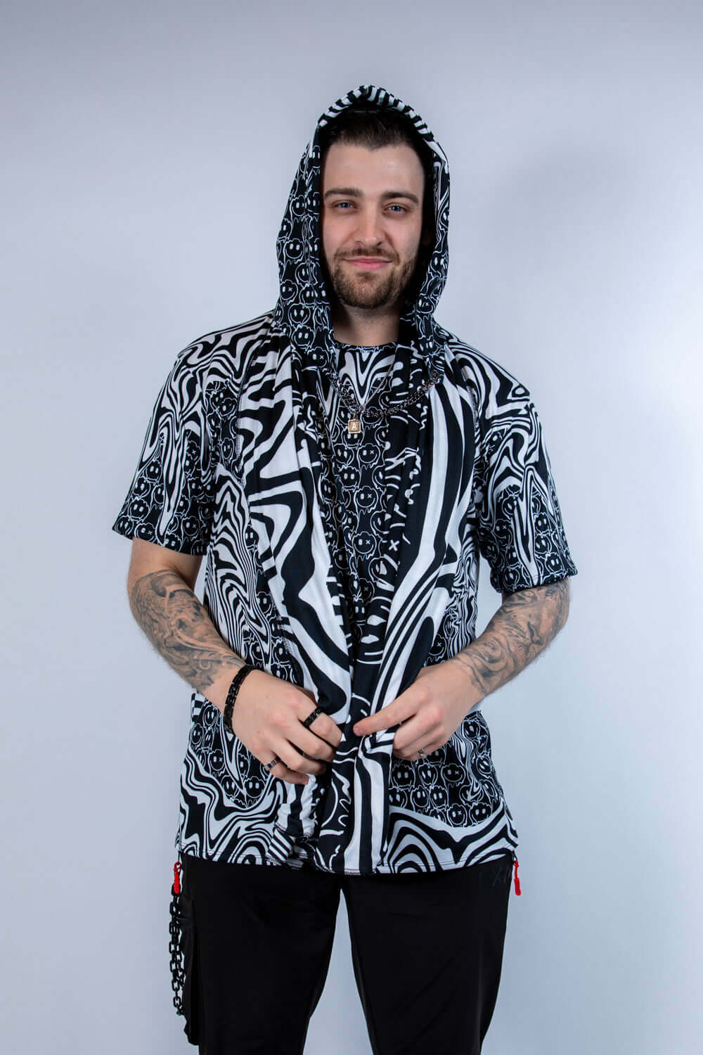 Model wearing the Meltdown Assassin Hood in full front view, holding the edges of the hood to show off the melty smiley print.