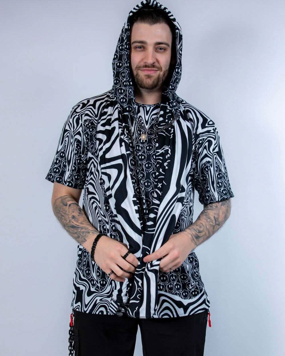 Model wearing the Meltdown Assassin Hood in full front view, holding the edges of the hood to show off the melty smiley print.